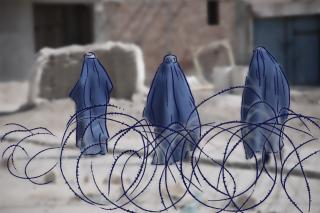 Drei Frauen in Burka, vor ihnen ist Stacheldraht angedeutet